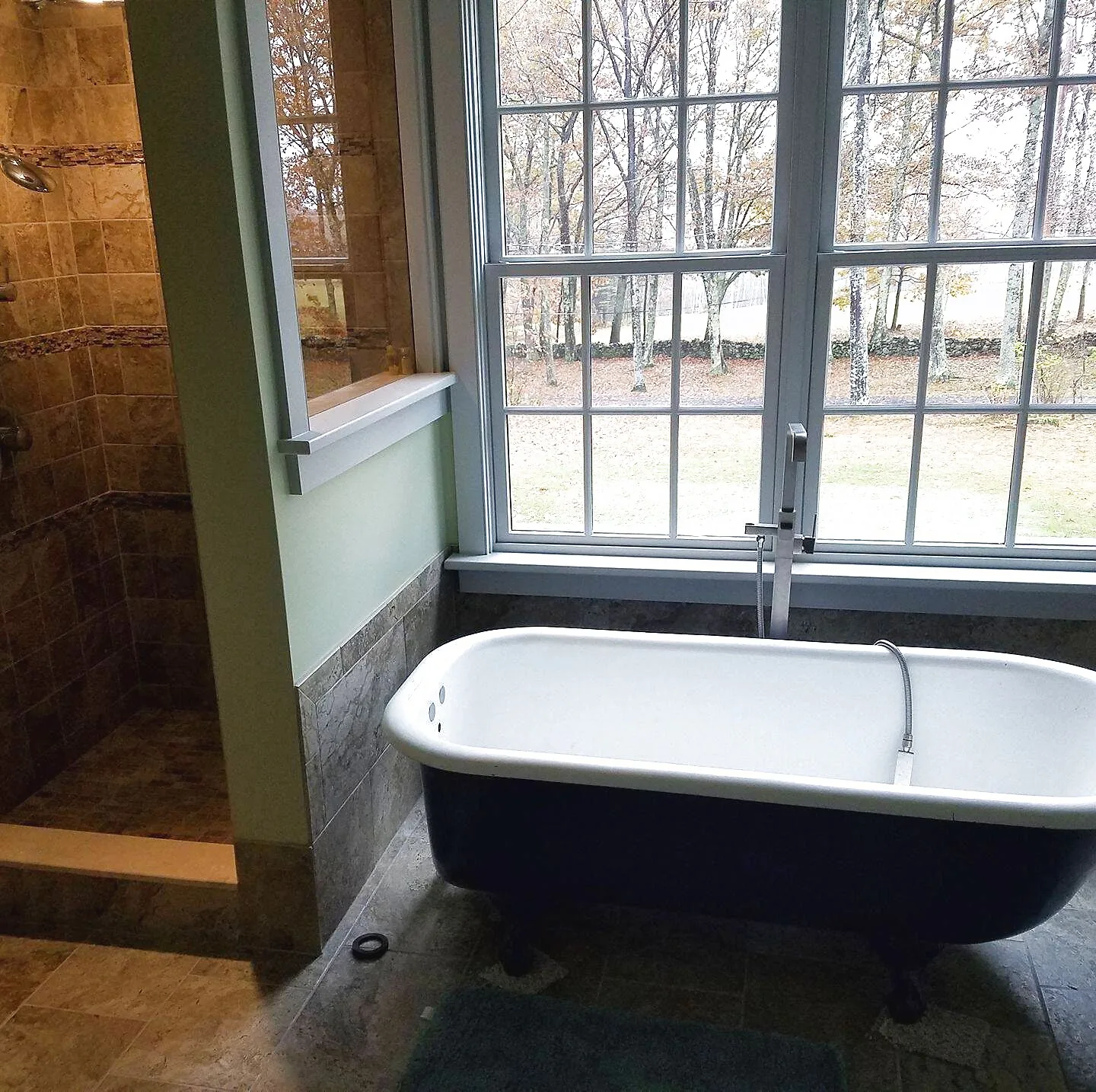A bathroom remodel by MCS Contracting with a freestanding tub framed by a window overlooking the Upper Valley