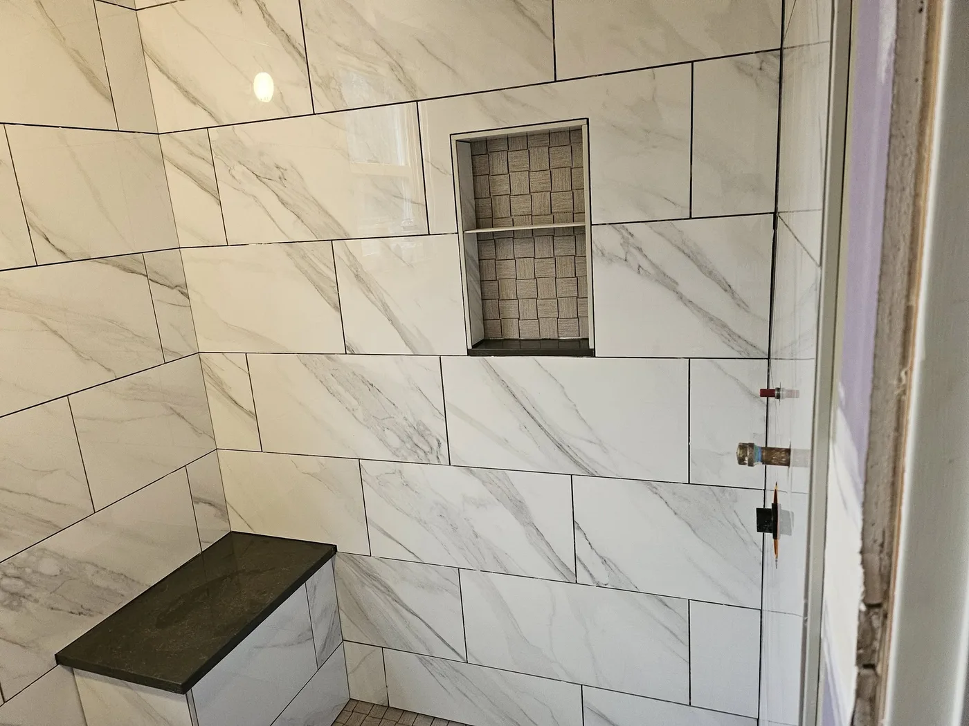 Large-format marble-look tile shower with a recessed niche, Upper Valley NH