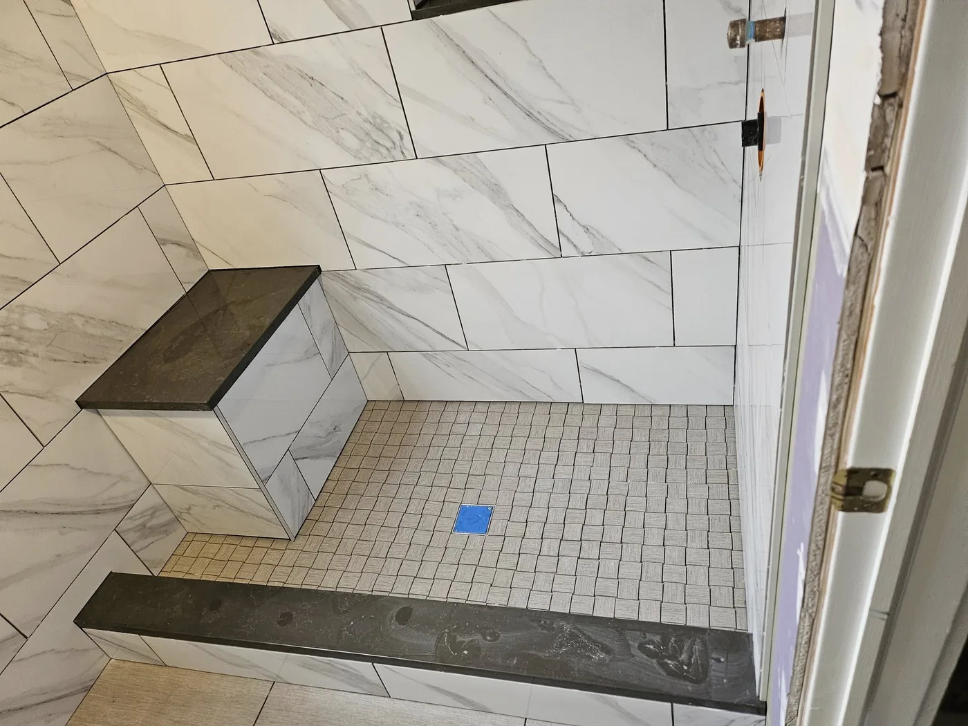 Marble-look tile walk-in shower with a built-in bench and glass door, Upper Valley NH