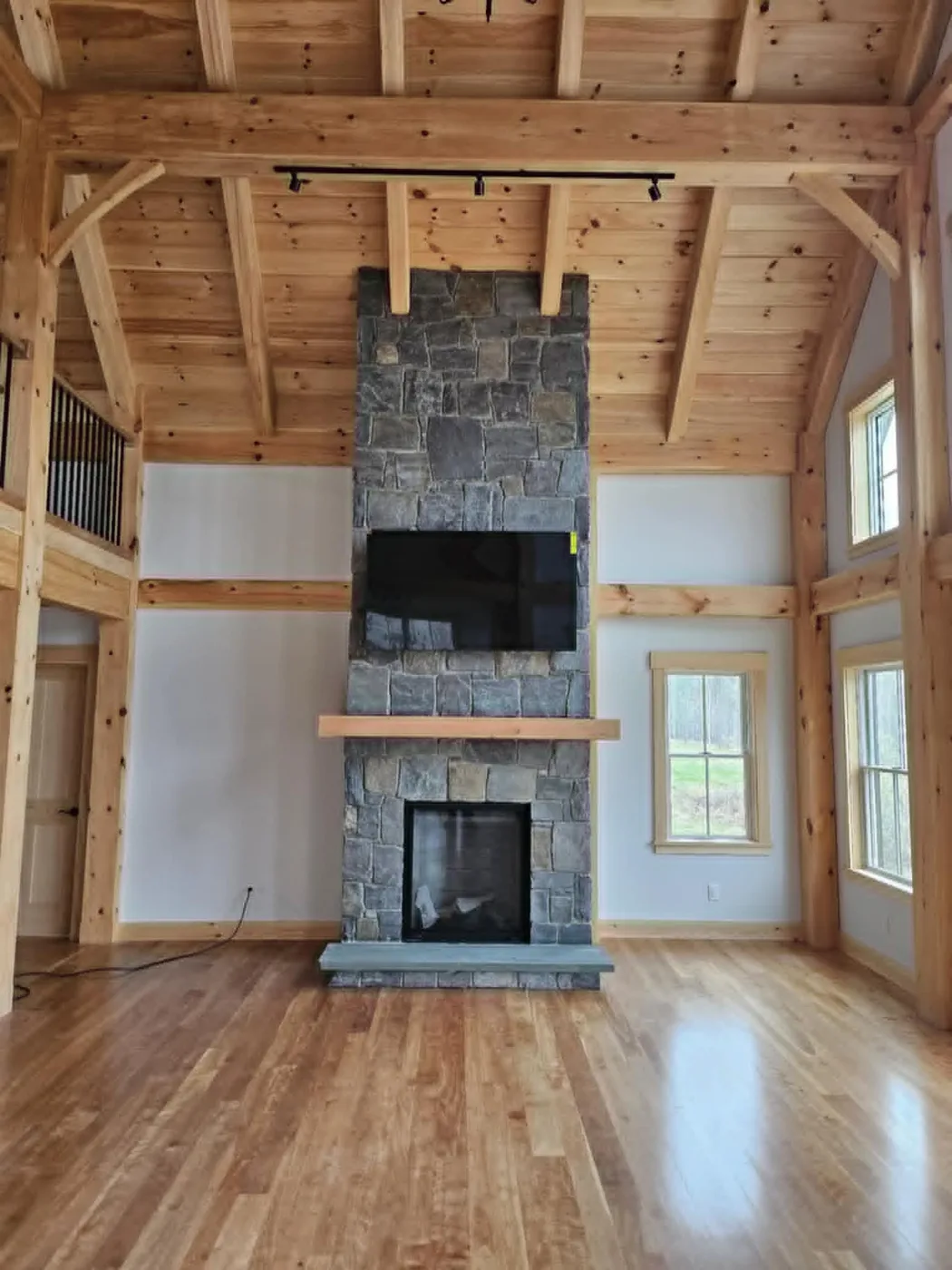 Timber-frame great room with a floor-to-ceiling stone fireplace, custom home in the Upper Valley NH