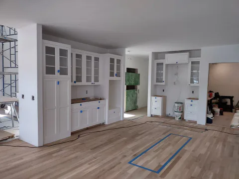 White custom kitchen with glass-front cabinetry and hardwood floors, Upper Valley NH