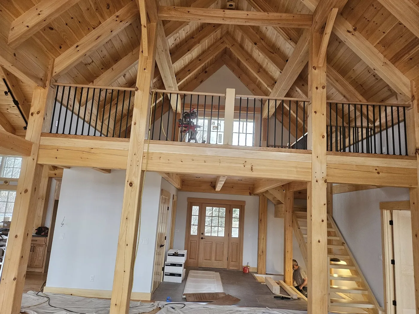 Post-and-beam timber-frame interior with large windows and an open staircase, Upper Valley NH