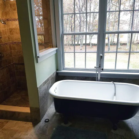 Bathroom remodel with a freestanding clawfoot tub and tile walk-in shower beneath a large window, Upper Valley NH