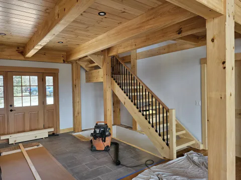 Custom timber-frame staircase with iron balusters beneath a pine ceiling, Upper Valley NH