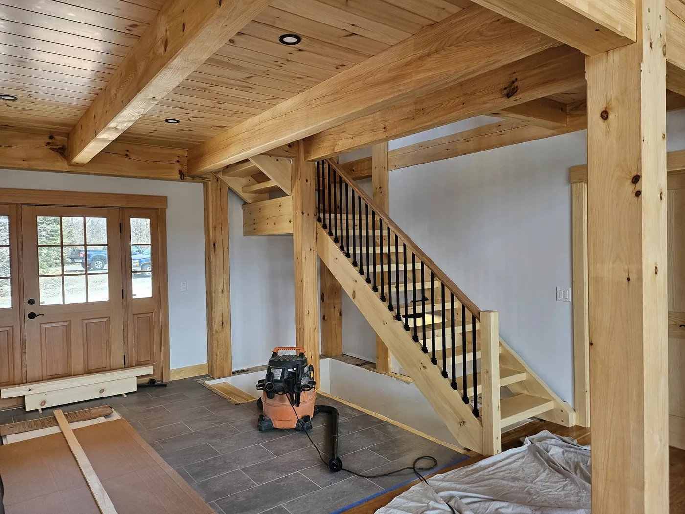 Custom timber-frame staircase with iron balusters beneath a pine ceiling, Upper Valley NH